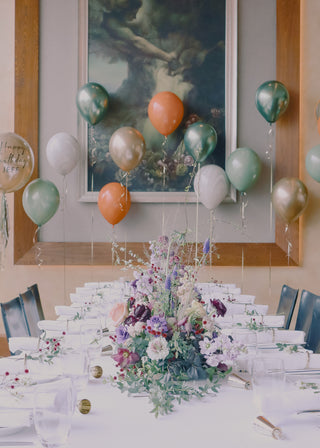 Elegant dining table with floral centerpiece and colorful balloons