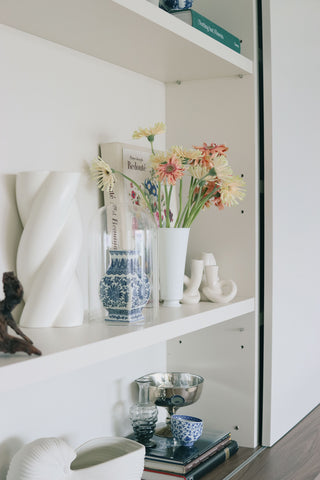 Shelf with decorative vases, books, and flowers