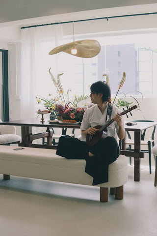 Person playing a traditional stringed instrument in a modern room