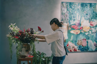 Florist arranging a vibrant flower display with artwork in the background